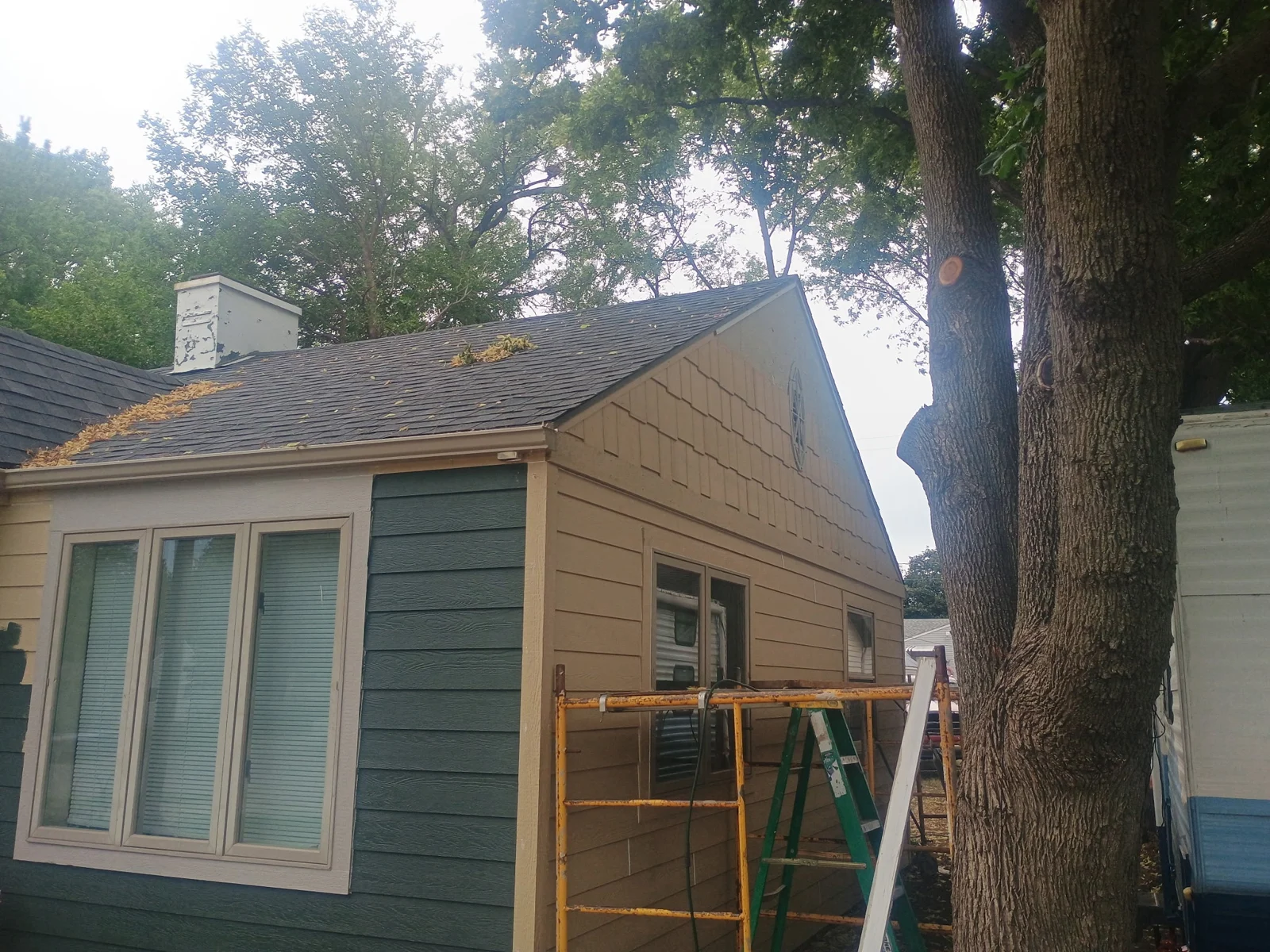 New siding, roofing, windows, and shake-style siding at the gable peak.